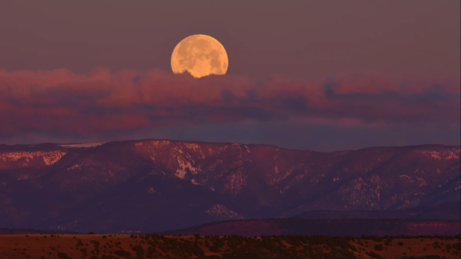 Grote volle maan boven een berglandschap tijdens een eerdere supermaan